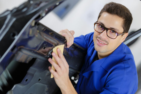 young service mechanic cleaning automobile car door
