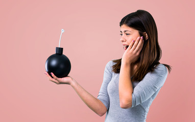 Teenager girl holding a bomb on pink background