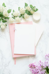 Flatlay in pink color with lilac flowers, notebooks and golden magnifier on marble background