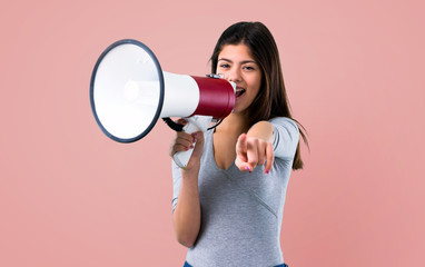Teenager girl holding a megaphone on pink background