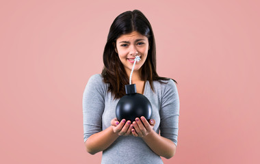 Teenager girl holding a bomb on pink background