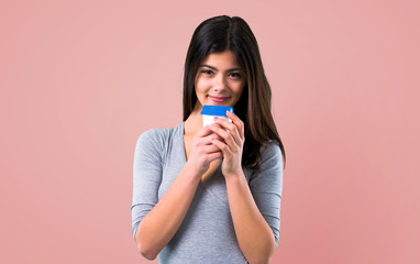 Teenager girl holding coffee to take away on pink background