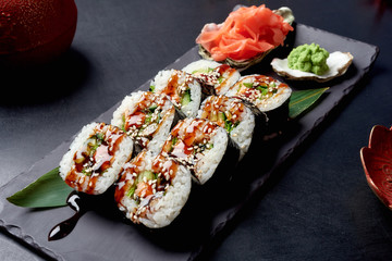 Tasty sushi roll on black stone plate and chinese sause with ginger and wassabi. Chinese cousine