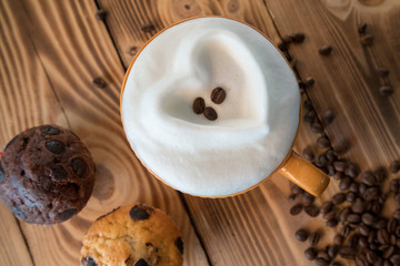 Obraz na płótnie Canvas Cup of coffee with foam in the form of a heart with cookies and coffee beans with coffee grinder on a wooden table
