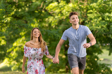 Happy couple holding hands and running in the  nature