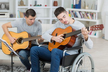 handicapped teenager and friend playing the guitar