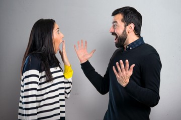 Couple making surprise gesture on grey background