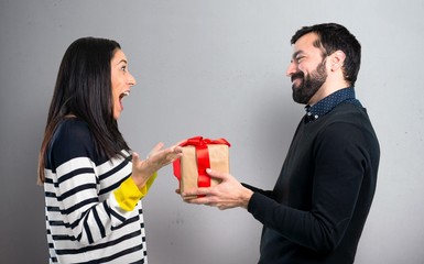 Man giving a gift to his girlfriend on grey background