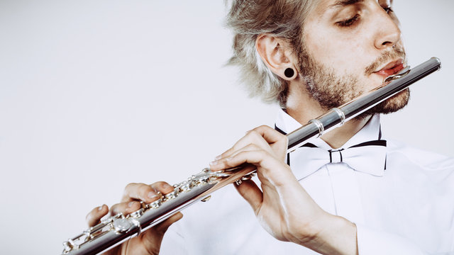 Male flutist playing his flute closeup