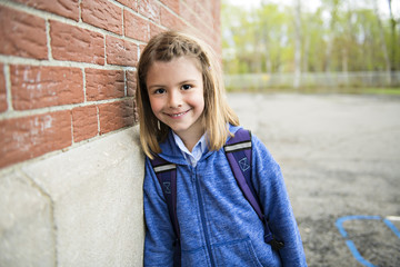 Portrait of cute girl with backpack outside of school