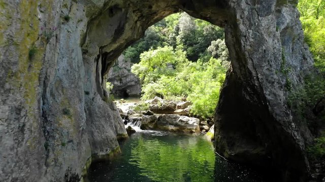 passage  au dessus d'une rivière à travers une arche naturelle creusée dans la montagne 