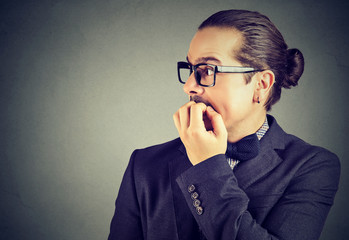 anxious young man biting his fingernails looking to the side