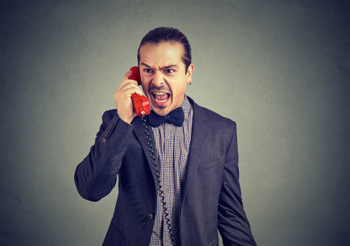 Young angry man yelling on the telephone