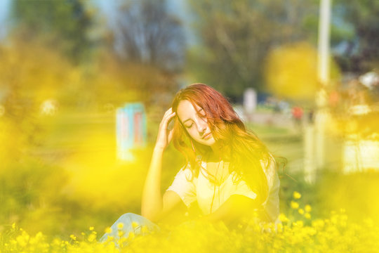 Young girl on a lawn field with yellow flowers