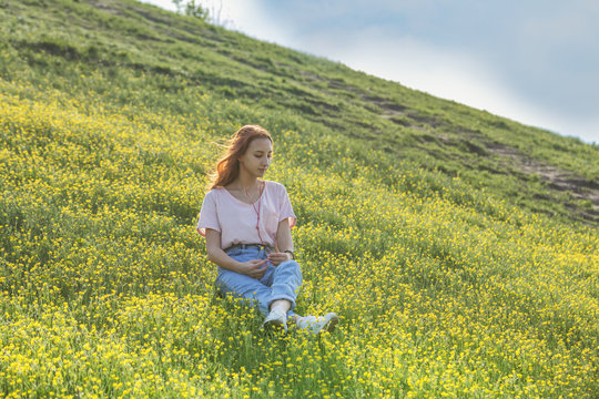 Young girl on a lawn field with yellow flowers