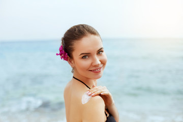 Woman Applying Sunscreen Creme on  Tanned  Shoulder. Skincare. Sun Protection. Girl Using Sun cream Lotion on Back