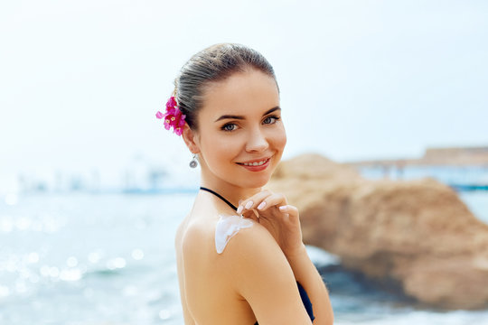 Woman smile applying sunscreen creme on  tanned  shoulder. Skincare. Body Sun protection sun cream. Bikini  woman smear  moisturizing lotion on back.