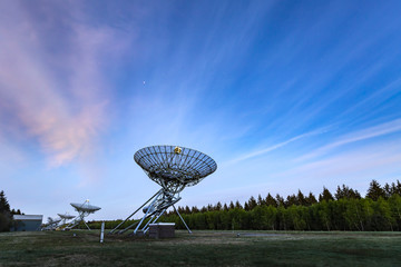 The Westerbork Synthesis Radio Telescope (WSRT) during dusk, with a light cloudy sky and stars a little visible