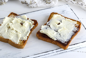 toasted bread with soft curd on a white wooden board