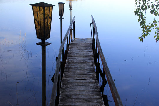 Wooden footbridge and lapms on the background of the water of the lake