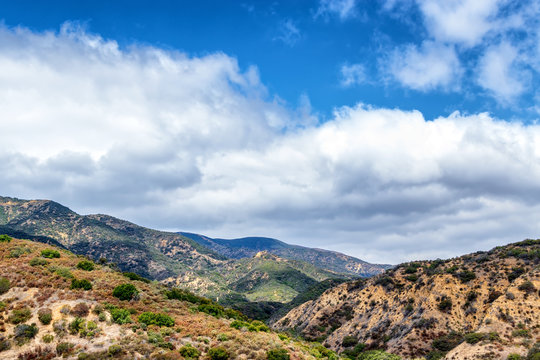 Rolling hills and mountains of California with puffy white clouds 
