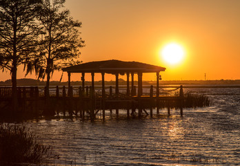 Fototapeta na wymiar Silhouetted Lakefront Dock at Orange Sunrise