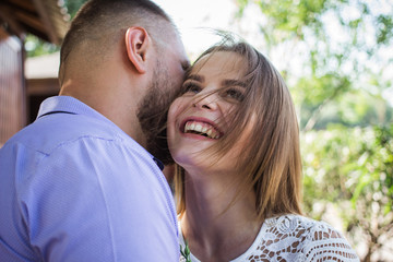 Fototapeta premium Young man whispering to woman or girlfriend, boyfriend telling surprising secret to his girl, man says nice words to his girlfriend, girl is smiling or laughing