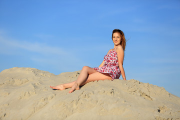Piękna kobieta w letniej sukience na szczycie piaszczystej wydmy. - obrazy, fototapety, plakaty
