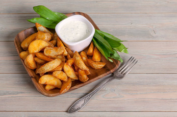 Slices of baked potatoes with leeks and garlic sauce in a wooden bowl