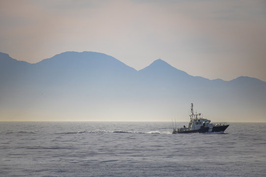 Beautiful sunrise over the ocean with boat and mountains in the background.