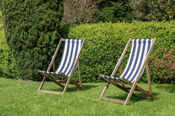 Two typical english deckchairs on lawn in garden