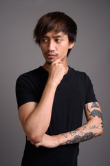 Young Asian man against gray background