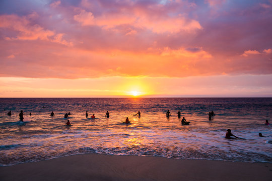 People swimming in ocean at sunset