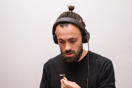 a man with a beard and a black t-shirt listening to music in headphones