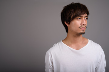 Fototapeta premium Young Asian man against gray background