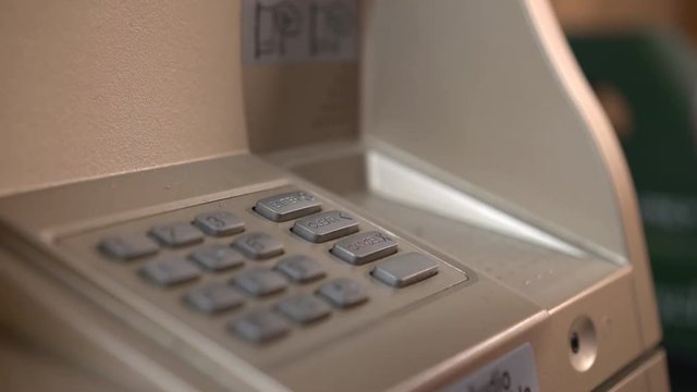 Female at bank ATM entering pin code number 4k
