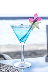 Blue cocktail in a martini glass with pink flower garnish and star fruit, plus plastic straws, at Apia, Upolu Island, Samoa, South Pacific