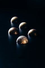 close up view of chocolate candies placed in row on black background