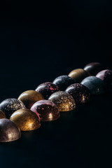 different chocolate candies placed in two rows on black background