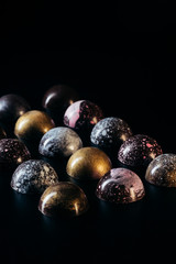 various chocolate candies placed in rows on black background