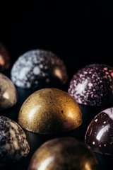 close up view of pile of different chocolate candies on black background