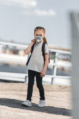 Obraz premium child in protective mask walking to school on bridge, air pollution concept