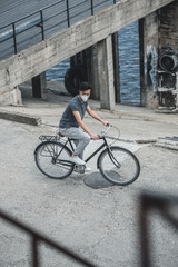 high angle view of asian teen in protective mask riding bicycle, air pollution concept