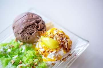The set of chocolate ball ice cream and white cream in the glass dish with green stick rice and vanille syrup topping. 