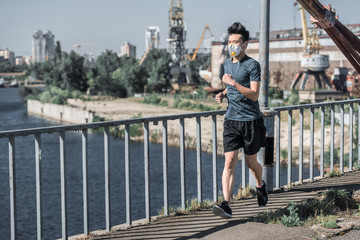 asian teen running in protective mask on bridge, air pollution concept