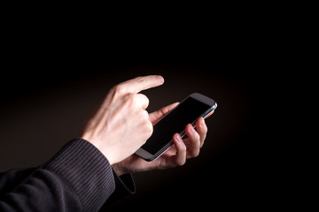 Man's hands using a smartphone on a black background