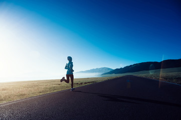 Young fitness sporty woman running on country road