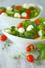  salad from tomatoes, cucumbers, mozzarella, parsley, basil in white cups on a white shabby wooden background.Vegetarian menu.Vegan food	