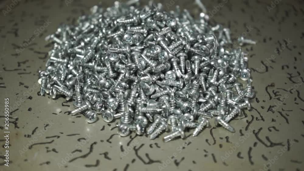 Poster screws rotating on a metal table and black background. Seamless loop.