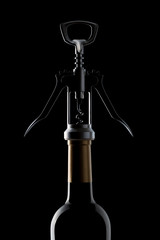 Corkscrew and wine bottle on a black background